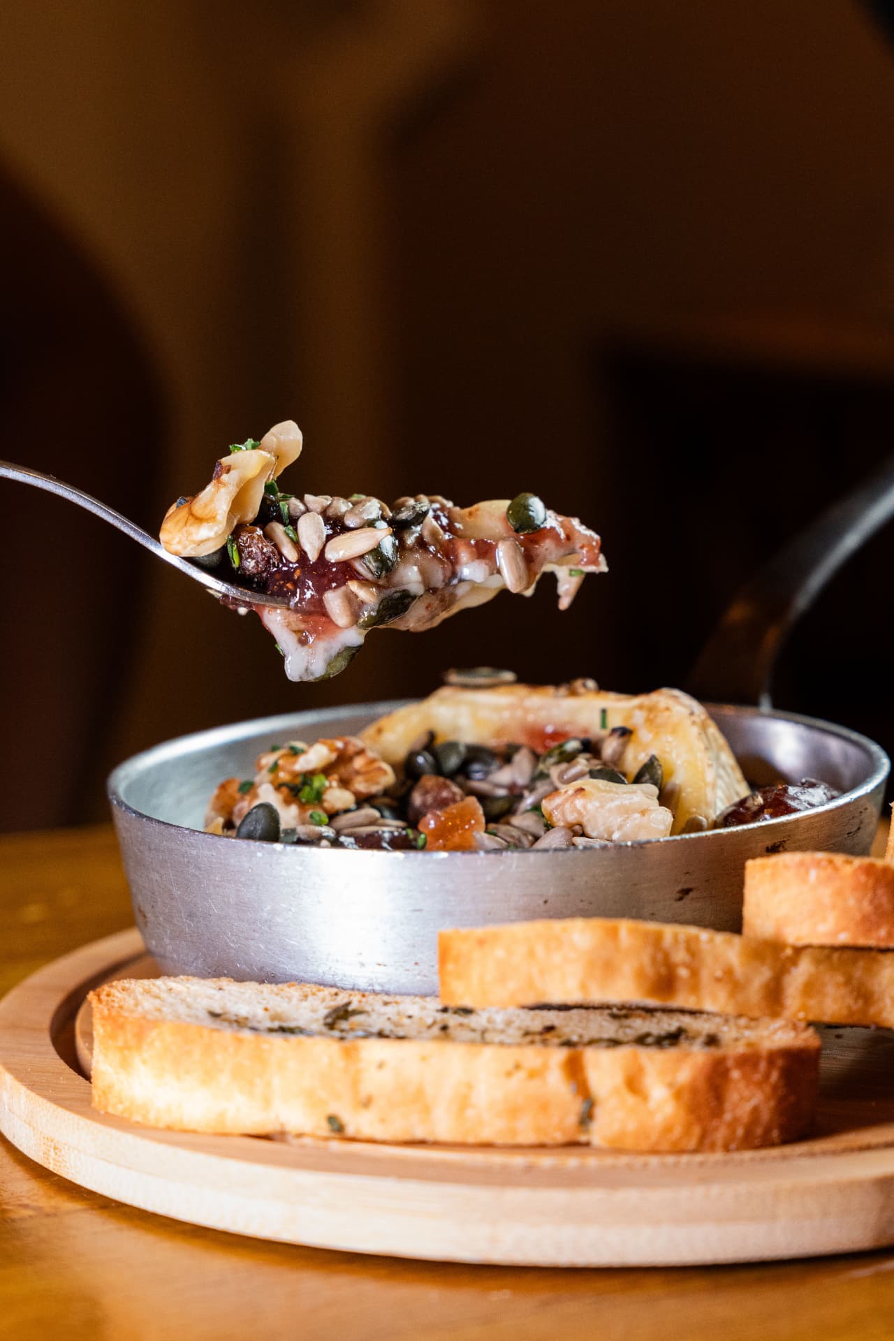 Spoonful of melted cheese with walnuts and seeds